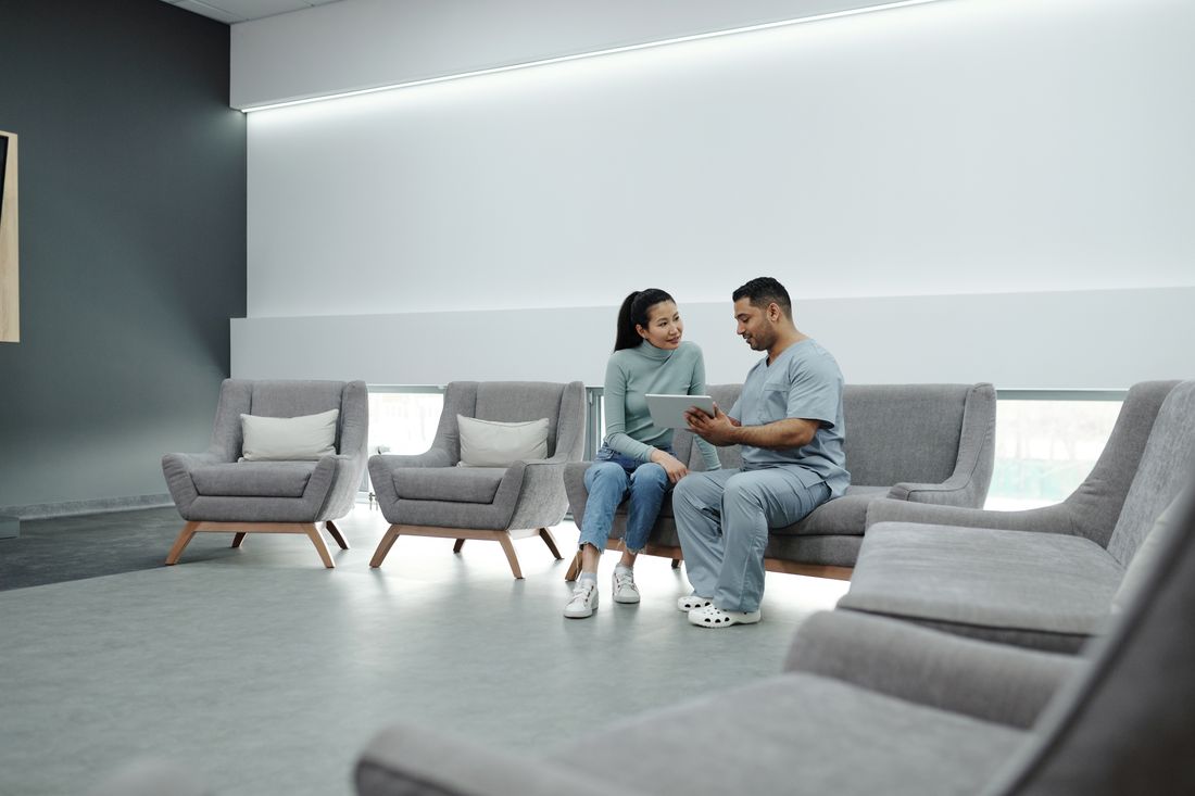 A staff member and a patient looking at a tablet in a clinic waiting area