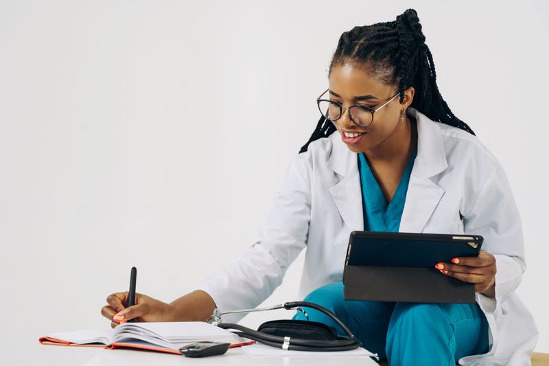 A doctor in a white coat noting a patient's details on a tablet