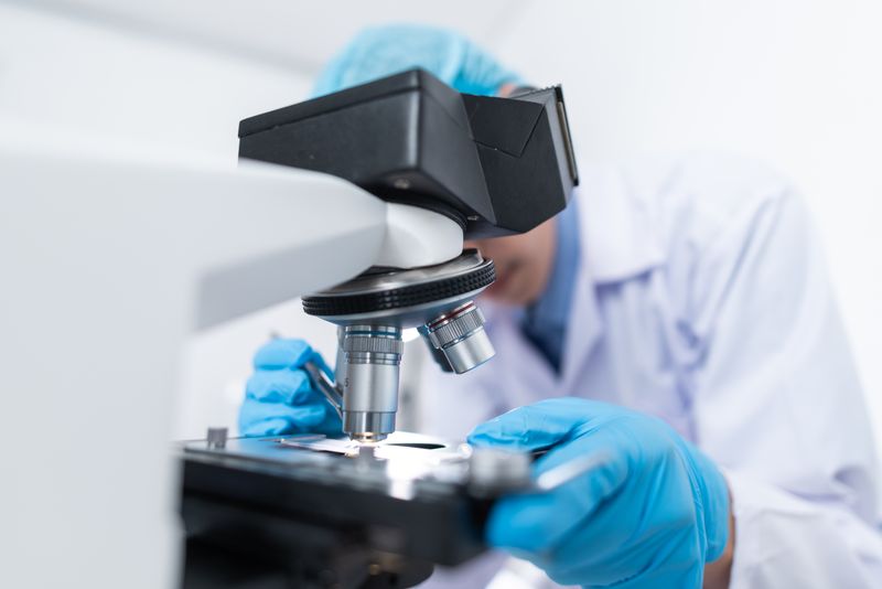 A laboratory technician examining a sample under a microscope