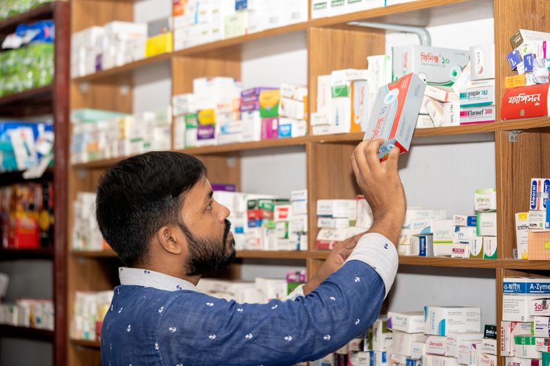 A pharmacist picking medicines from a shelf